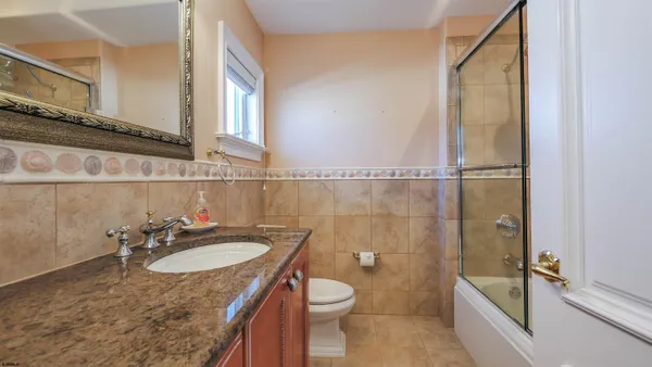 a bathroom with a granite countertop sink a large mirror and a bathtub next to a window