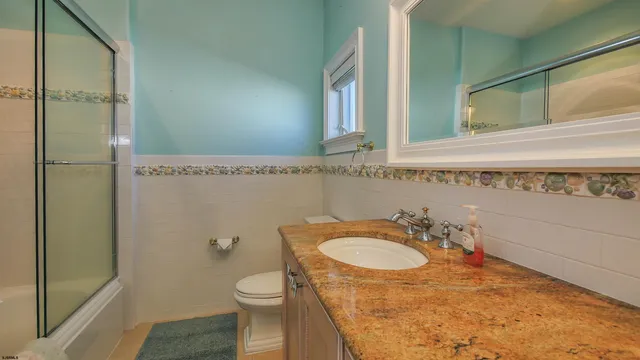 a bathroom with a granite countertop sink toilet and shower