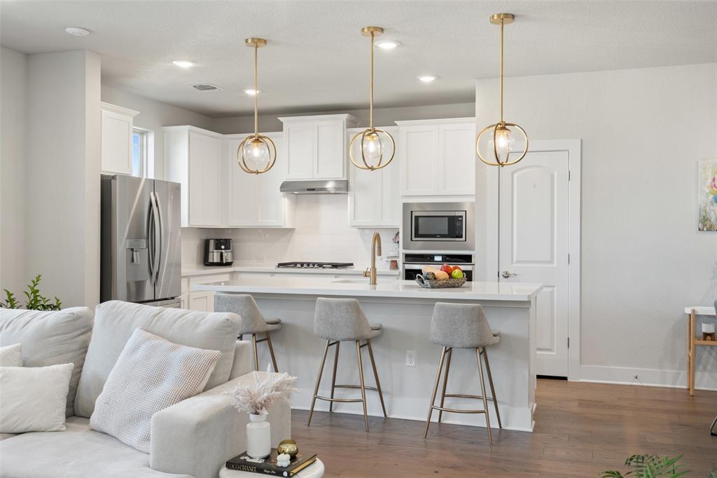8419 Laughlin Lane Austin, TX 78744 - Photo 40 of 40 Kitchen featuring open floor plan, white cabinetry, stainless steel appliances, decorative backsplash, and a breakfast bar area