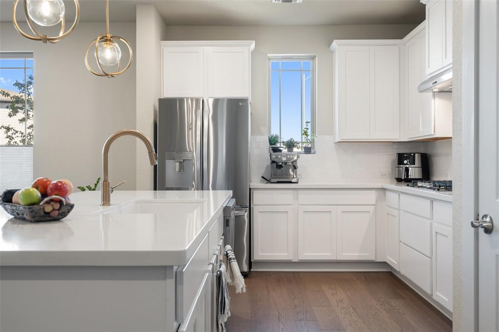8419 Laughlin Lane Austin, TX 78744 - Photo 16 of 40 Kitchen featuring dark wood-style flooring, white cabinetry, appliances with stainless steel finishes, and decorative light fixtures