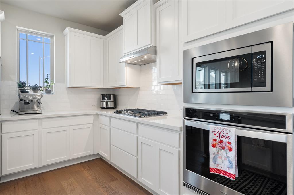 8419 Laughlin Lane Austin, TX 78744 - Photo 17 of 40 Kitchen featuring stainless steel appliances, white cabinetry, dark wood-style flooring, and backsplash