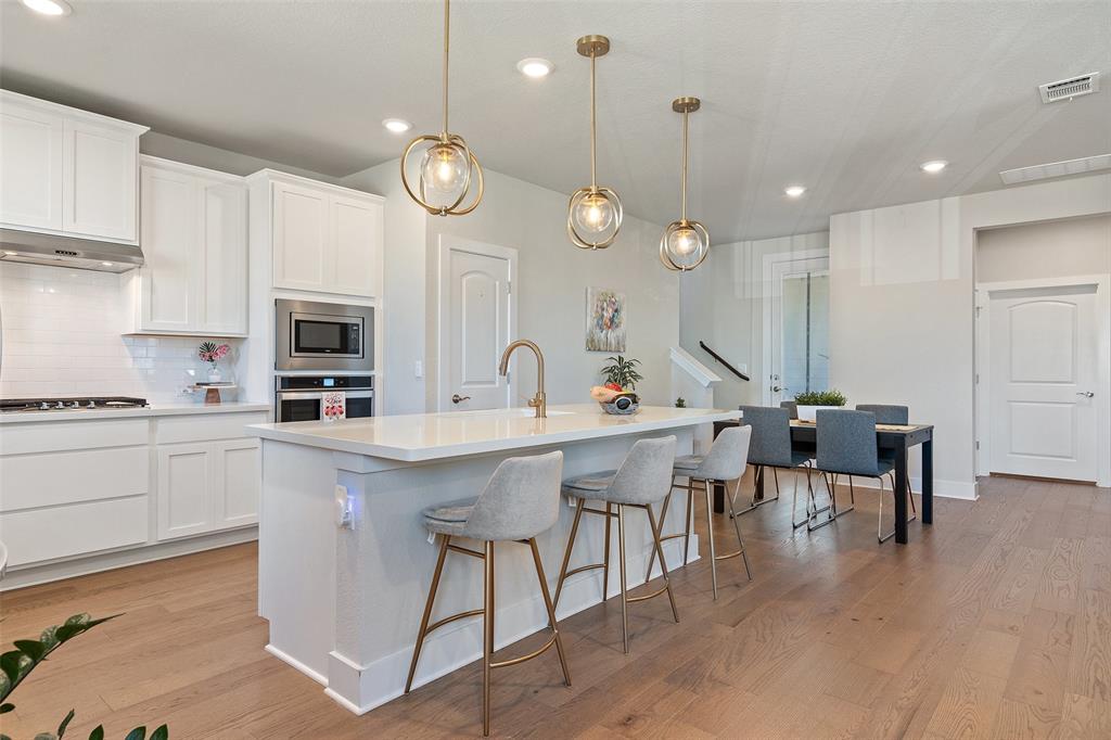 8419 Laughlin Lane Austin, TX 78744 - Photo 19 of 40 Kitchen featuring white cabinetry, hanging light fixtures, a kitchen breakfast bar, backsplash, and recessed lighting