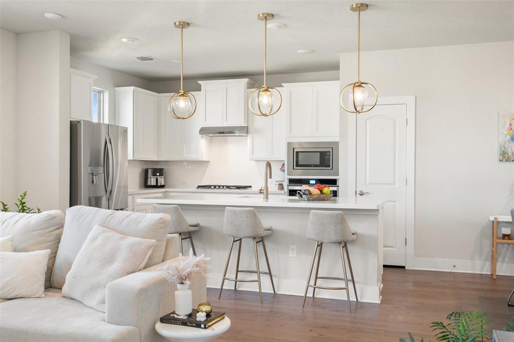 8419 Laughlin Lane Austin, TX 78744 - Photo 39 of 40 Kitchen with open floor plan, white cabinetry, stainless steel appliances, decorative backsplash, and a kitchen bar