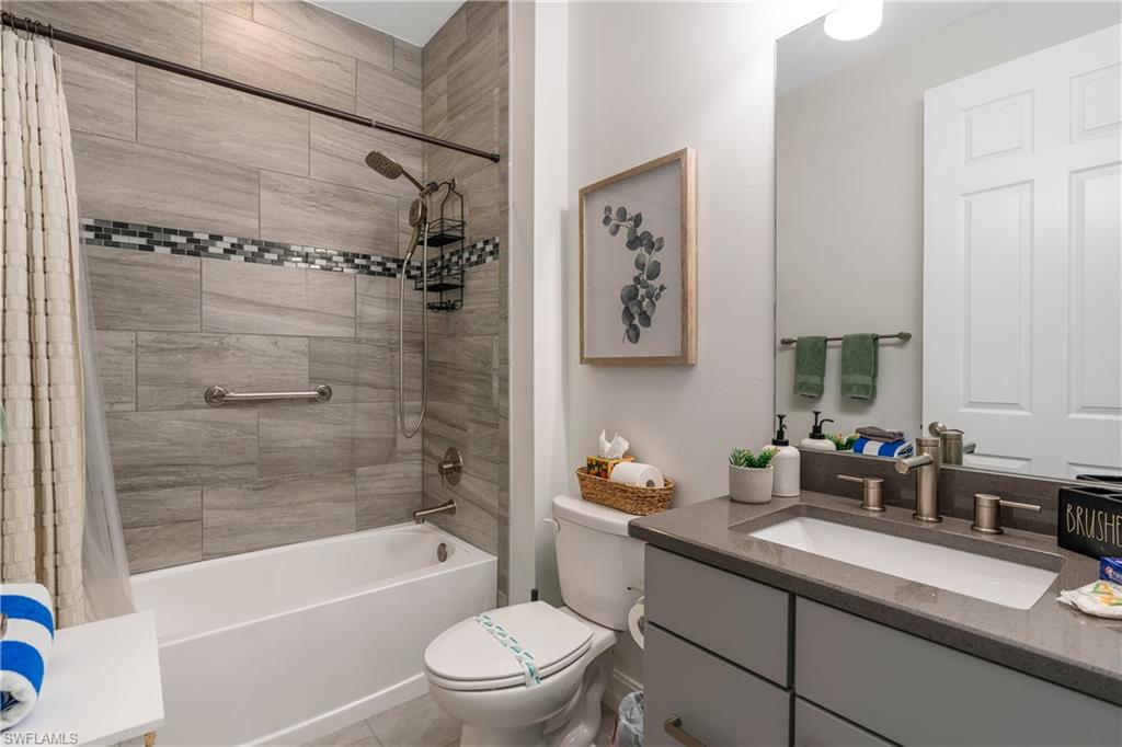 14837 Windward Lane Naples, FL 34114 - Photo 20 of 39 a bathroom with a granite countertop sink a toilet and bathtub