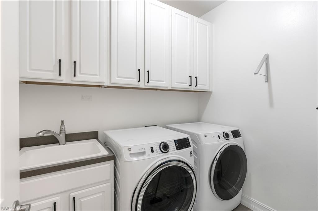 14837 Windward Lane Naples, FL 34114 - Photo 22 of 39 a view of washer and dryer with kitchen in the background