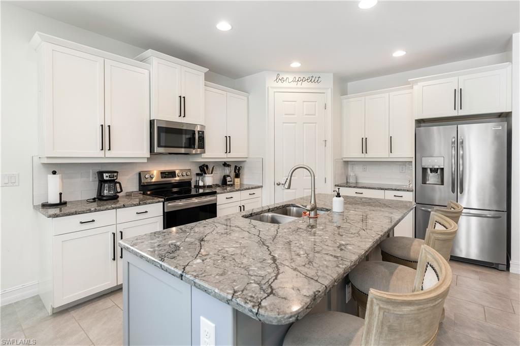 14837 Windward Lane Naples, FL 34114 - Photo 6 of 39 a kitchen with stainless steel appliances granite countertop a stove top oven a refrigerator a sink and white cabinets with wooden floor