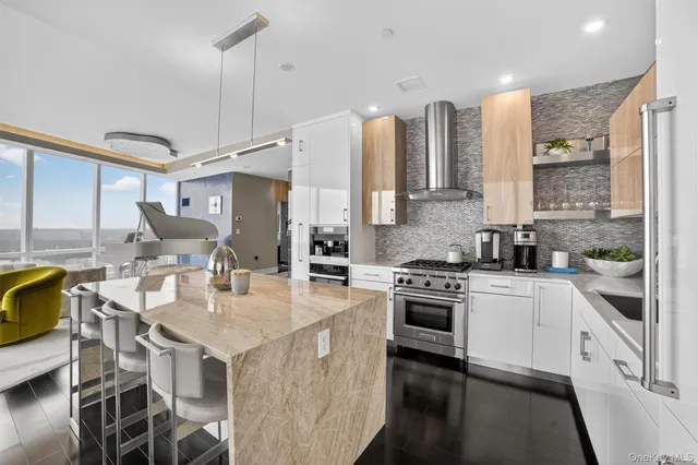 a kitchen with stainless steel appliances kitchen island granite countertop a stove a sink dishwasher and a refrigerator with wooden floor