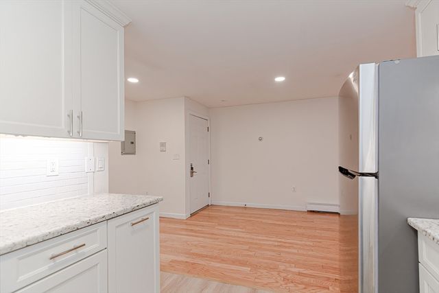 a kitchen with granite countertop white cabinets and refrigerator