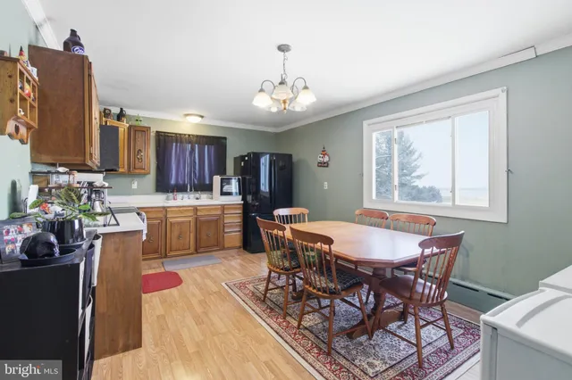 a dining room with wooden floor a chandelier a wooden table and chairs