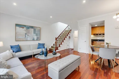a living room with furniture and a dining table with wooden floor