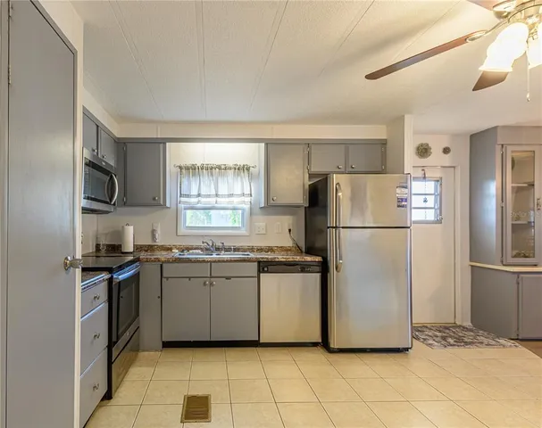 a kitchen with granite countertop a refrigerator and a stove top oven