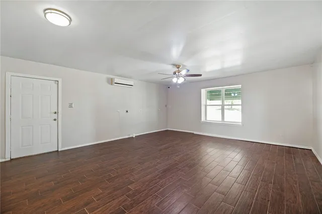 an empty room with wooden floor chandelier fan and windows