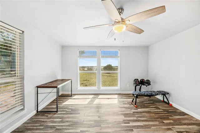 a view of an empty room with a window and wooden floor
