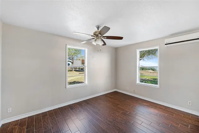 a view of an empty room with window and wooden floor