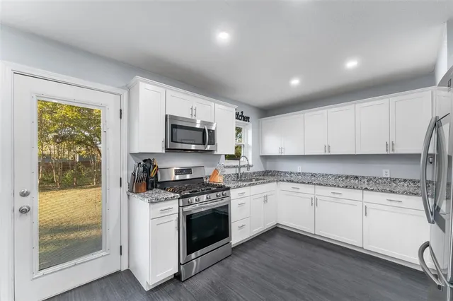 a kitchen with granite countertop white cabinets and white appliances