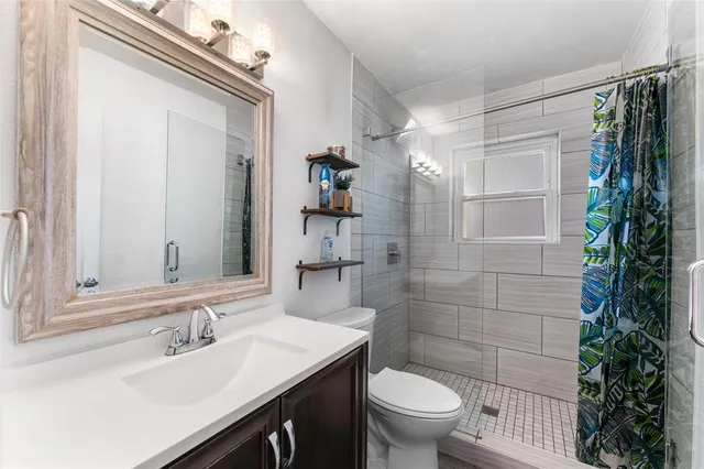 a bathroom with a sink a toilet a shower and a mirror