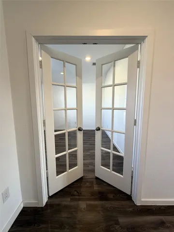 a view of an empty room with wooden floor and windows