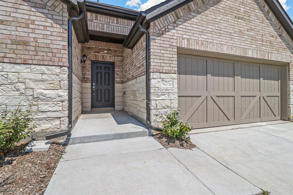 2755 Rambling Road Celina, TX 75009 - Photo 2 of 15 Brick and stone veneer exterior with a paneled garage door, covered entryway, and concrete walkway