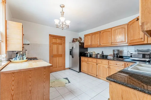 a kitchen with stainless steel appliances granite countertop a stove top oven a sink dishwasher and a refrigerator with wooden cabinets