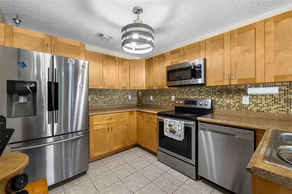 a kitchen with stainless steel appliances granite countertop a refrigerator a stove a sink and dishwasher