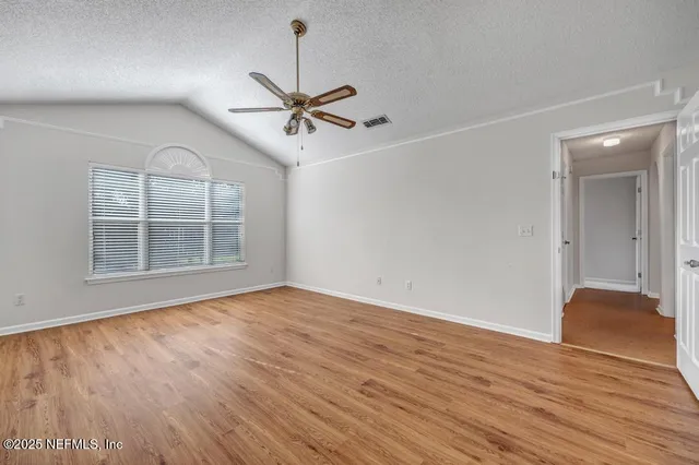 a view of empty room with wooden floor and fan