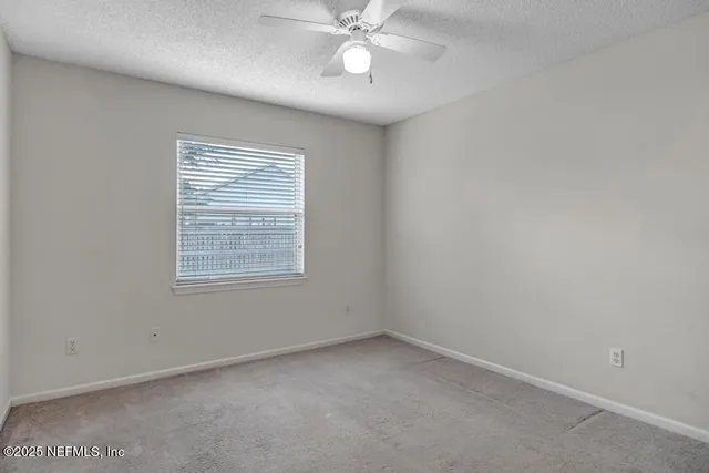 an empty room with a window and a fan