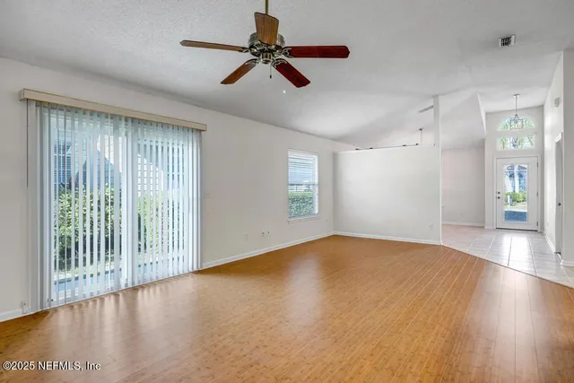 a view of an empty room with a window and wooden floor