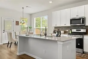 a kitchen with stainless steel appliances granite countertop a stove a sink a microwave a dining table and chairs