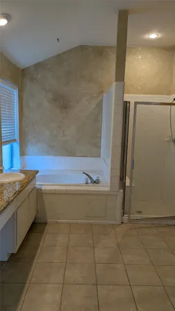 a bathroom with a granite countertop bathtub and shower