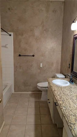 a bathroom with a granite countertop sink a toilet and a shower