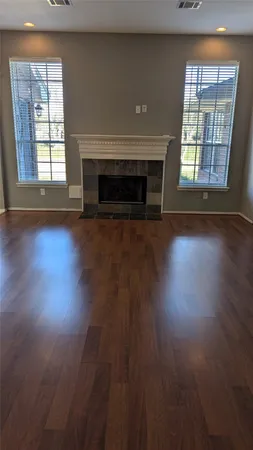 an empty room with wooden floor fireplace and windows