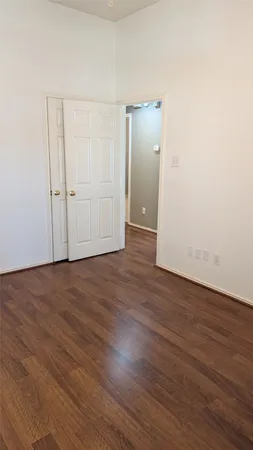 an empty room with wooden floor & closet area