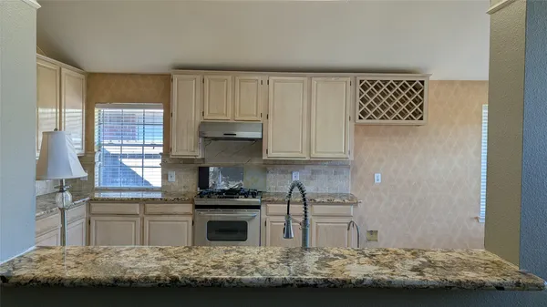 a kitchen with kitchen island granite countertop a stove and a wooden cabinets