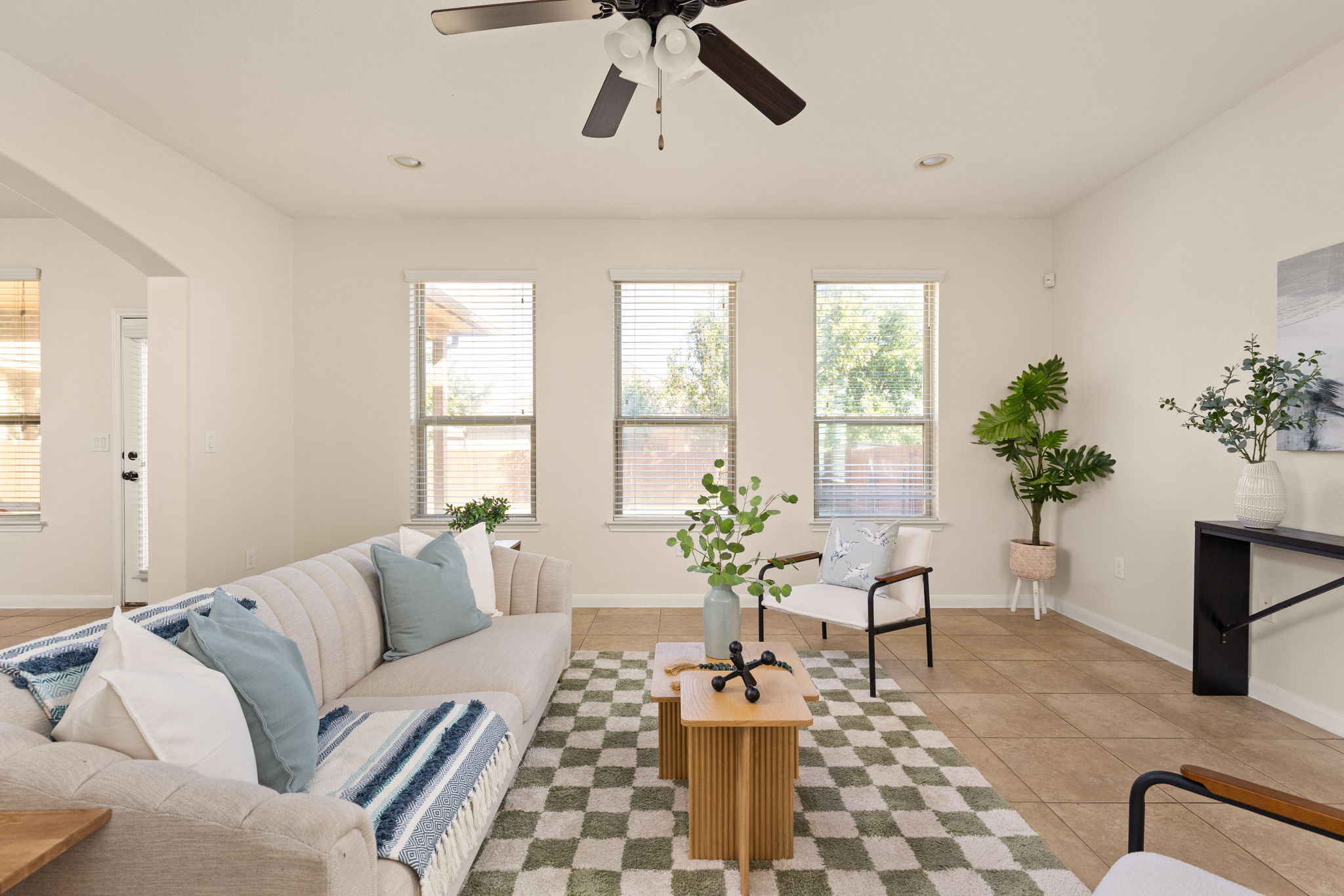 2400 Leonards Pass Leander, TX 78641 - Photo 9 of 40 A cheerful living room featuring large windows, durable tile flooring, and a ceiling fan for year-round comfort.