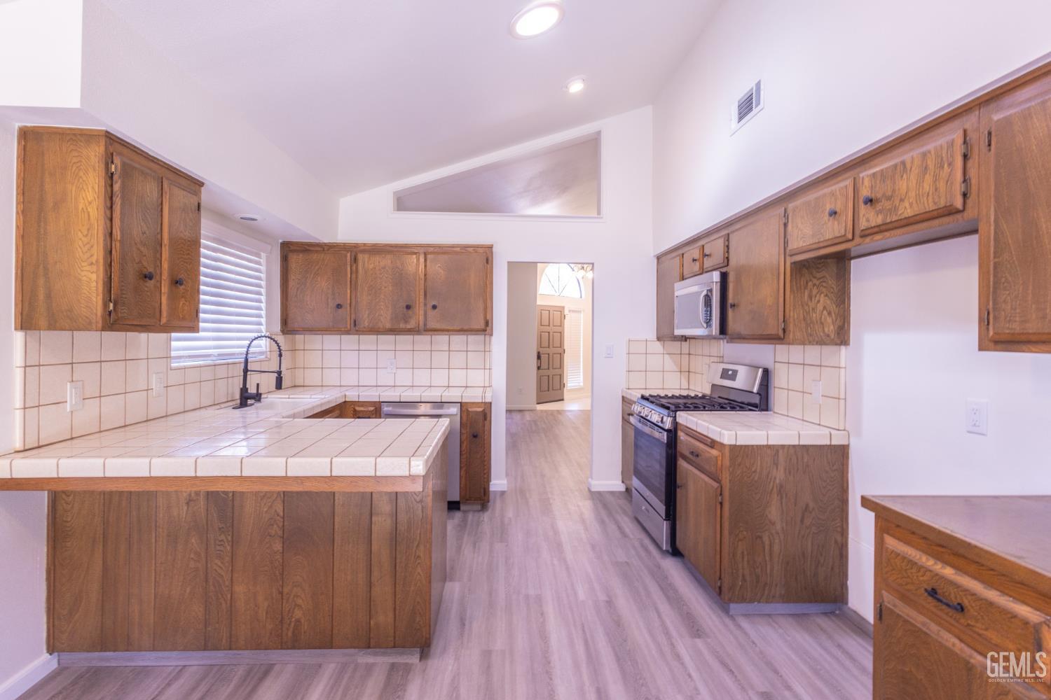 Undisclosed Address Bakersfield, CA 93309 - Photo 14 of 37 a large kitchen with stainless steel appliances granite countertop a sink stove and wooden floor