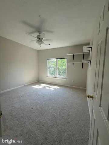 an empty room with a window and a ceiling fan