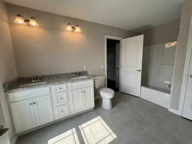 a spacious bathroom with a granite countertop sink a toilet and a mirror