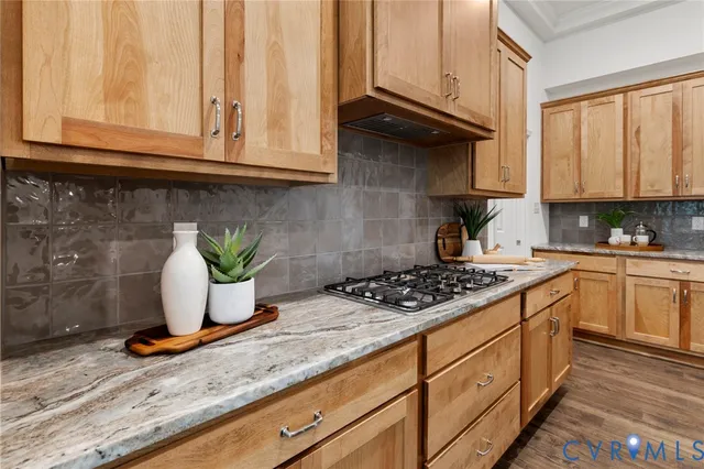 a kitchen with granite countertop a stove a sink dishwasher and cabinets with wooden floor