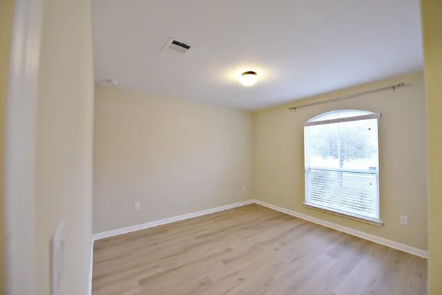 an empty room with wooden floor and windows