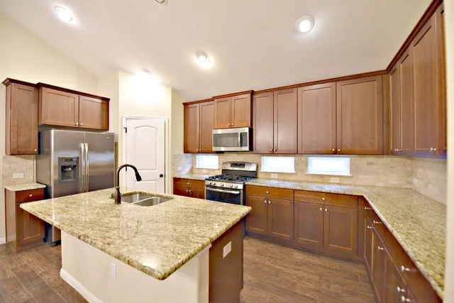 a kitchen with kitchen island granite countertop a sink stove refrigerator and cabinets
