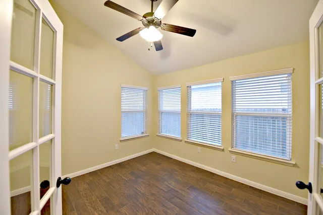 a view of an empty room with a window and wooden floor
