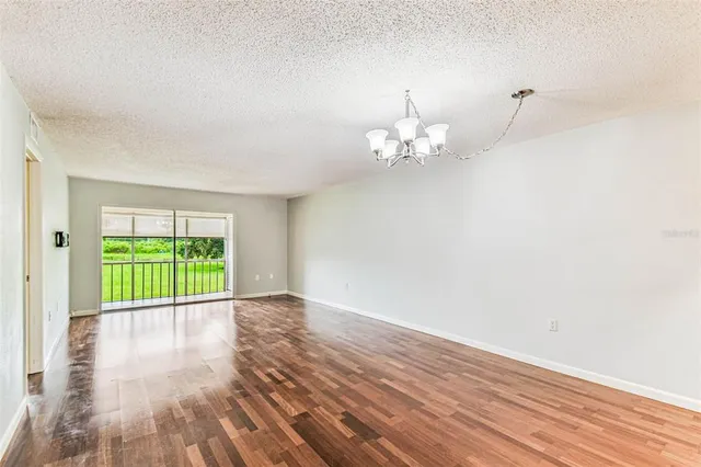 a view of an empty room with wooden floor and fan