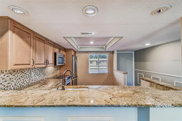 a kitchen with granite countertop stainless steel appliances a stove sink and refrigerator