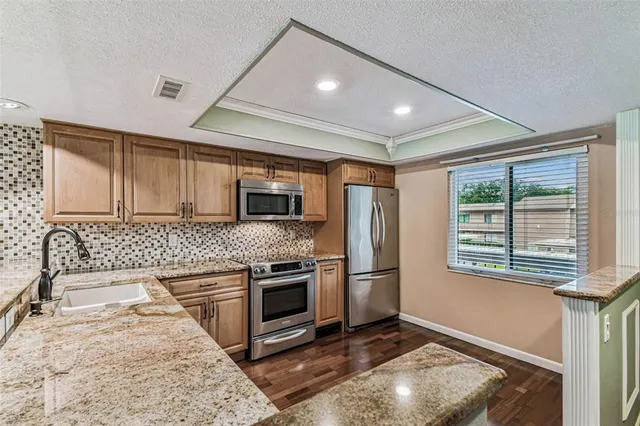 a kitchen with stainless steel appliances granite countertop a refrigerator stove a sink and dishwasher with wooden floor