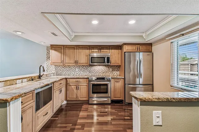 a kitchen with granite countertop wooden cabinets stainless steel appliances and a window