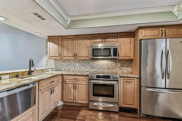 a kitchen with stainless steel appliances granite countertop a refrigerator and a stove top oven