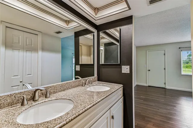 a bathroom with a granite countertop sink a mirror toilet and bathtub