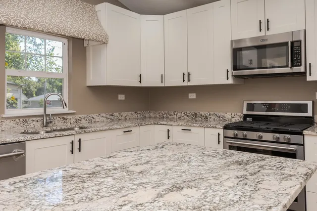 a kitchen with stainless steel appliances granite countertop a stove top oven a sink a microwave and a granite counter tops