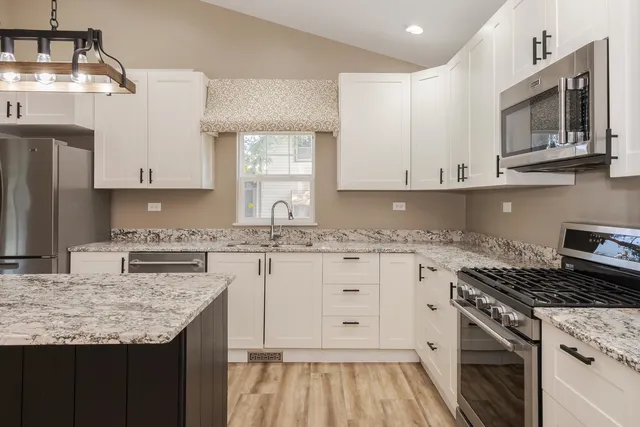 a kitchen with granite countertop a sink stove and cabinets