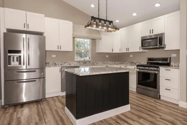 a kitchen with stainless steel appliances granite countertop a refrigerator a stove a sink and a microwave